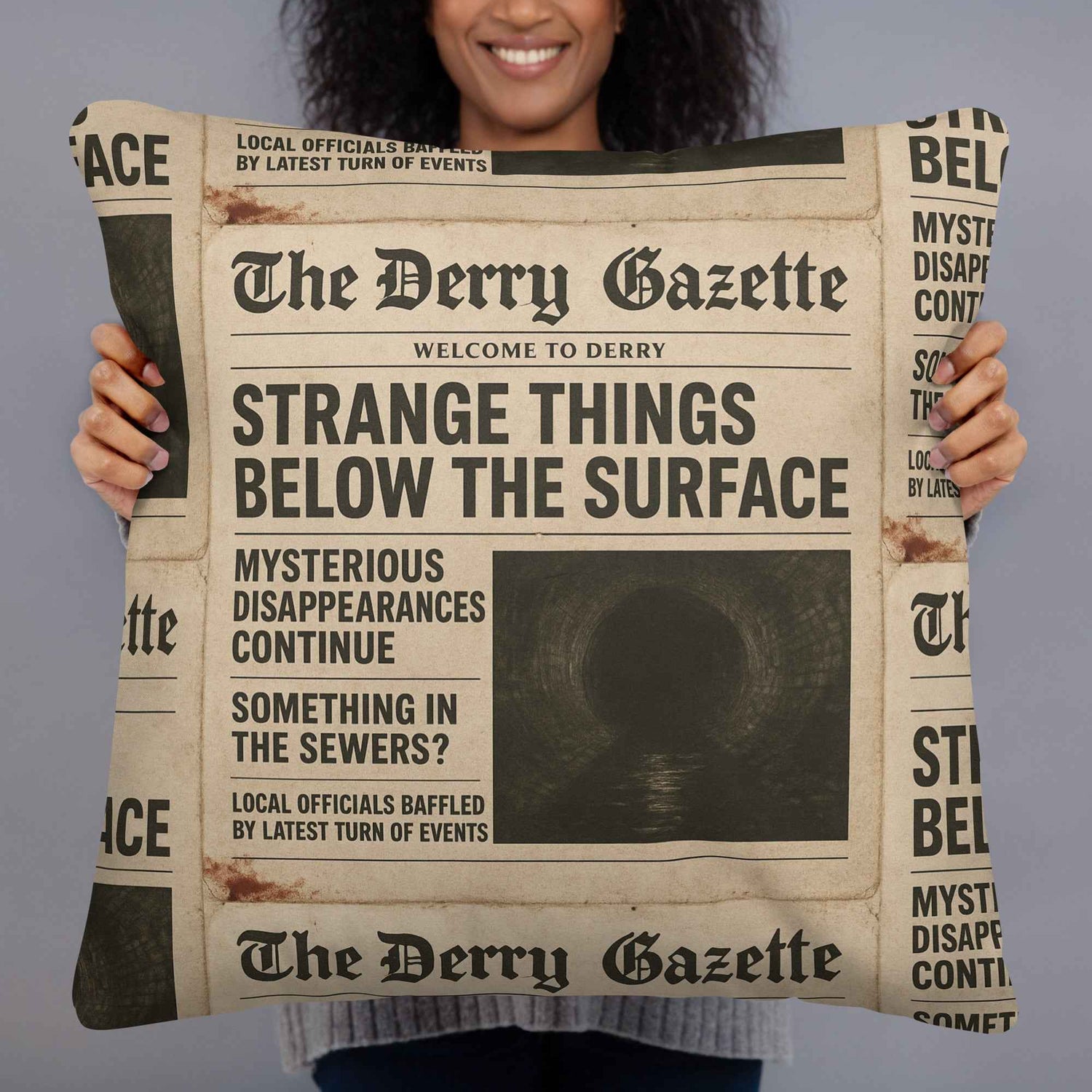 Woman holding a pillow featuring “The Derry Gazette” design, showcasing the retro horror theme of Derry, Maine.